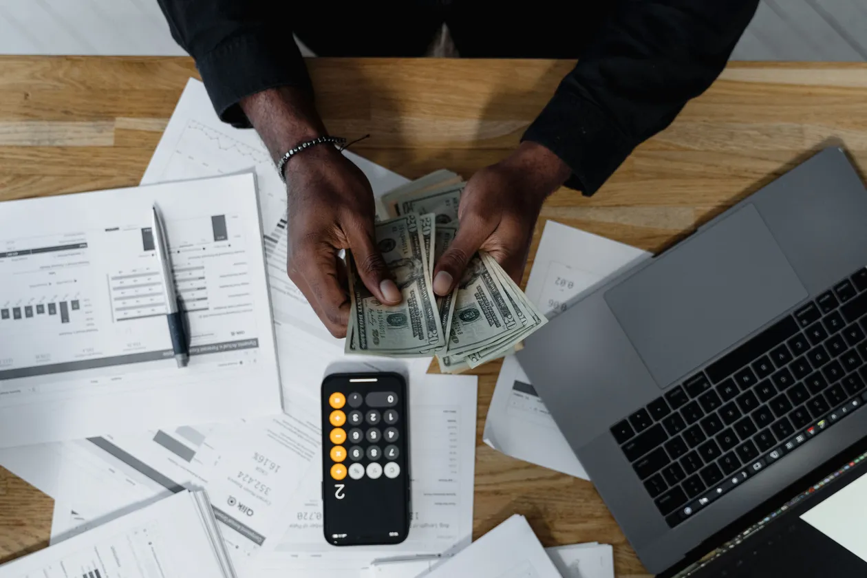 A person counting a stack of US dollar bills