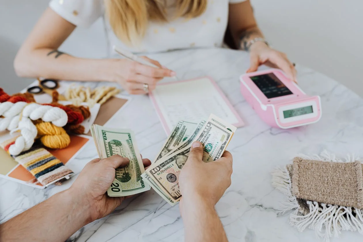 Person counting dollar bills on a desk — revenue-based financing concept