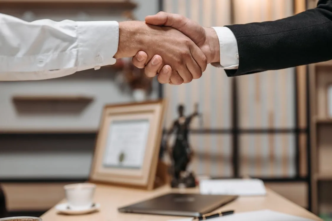 Professionals shaking hands in an office, symbolizing regulatory agreement and legal implementation