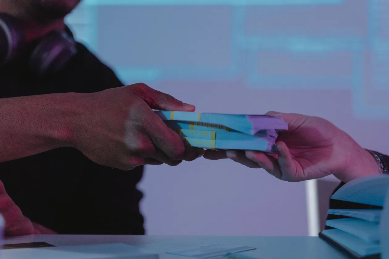 Close-up of hands exchanging money in a dimly lit setting