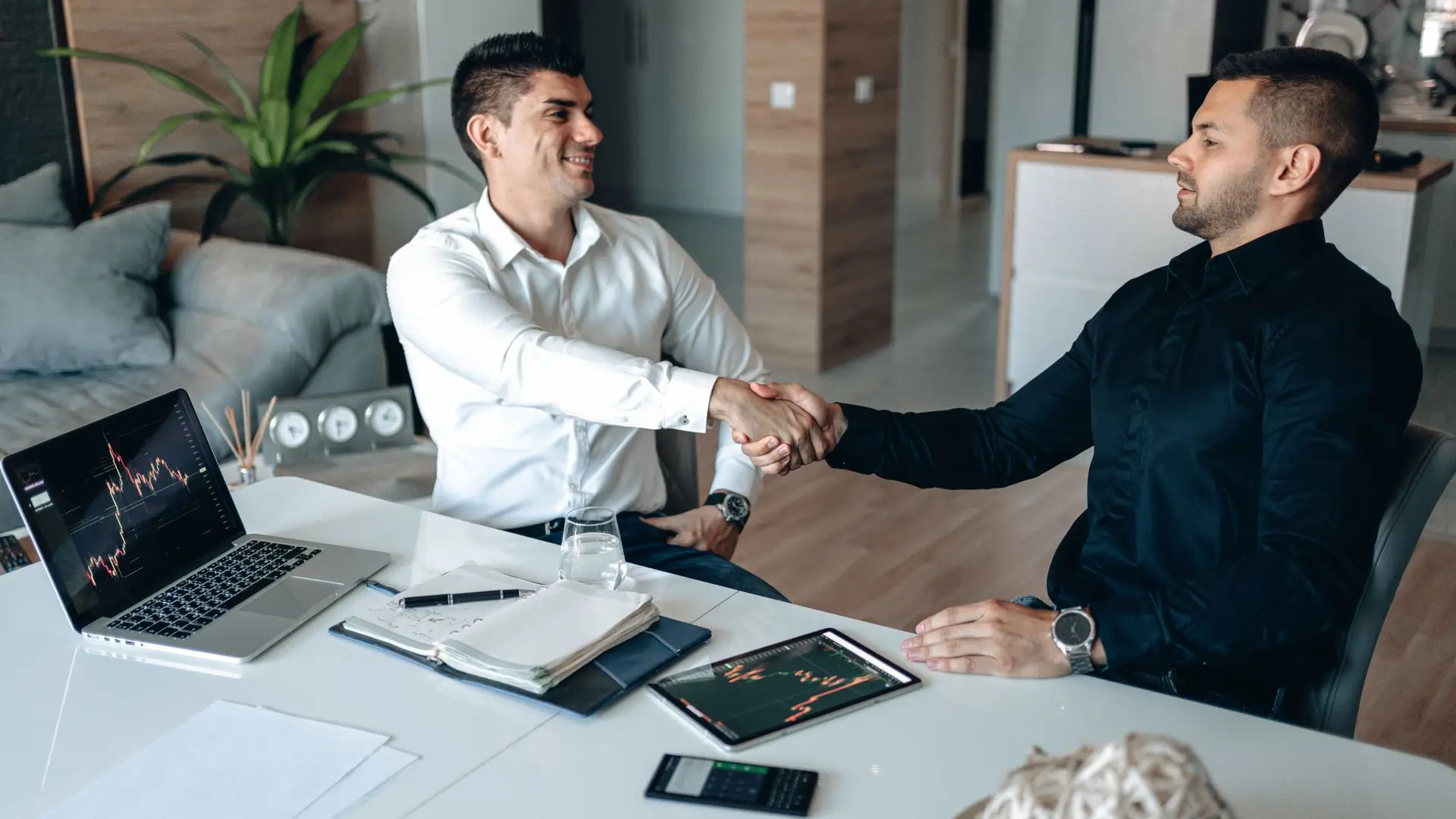 Two men shaking hands in a business agreement, symbolizing trust and partnership in a professional setting.
